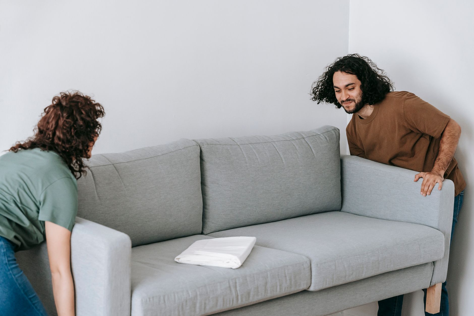 Two people carrying a sofa during clearance